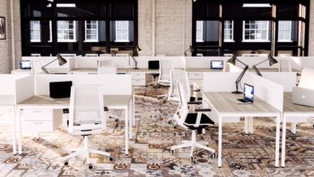 Oficina de gran tamaño en la que hay múltiples puestos de trabajo, cada uno con un escritorio individual separado por pantallas