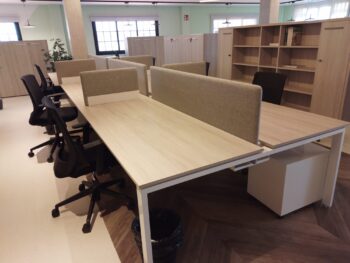 Mesas de oficina con acabado efecto madera y separadas por mamparas de una tonalidad a juego