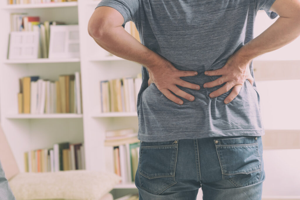 Hombre en su oficina con dolor lumbar y molestias en la espalda